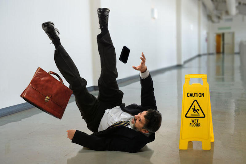 Fallen from grace image showing a businessman falling by a fall sign on a wet flour