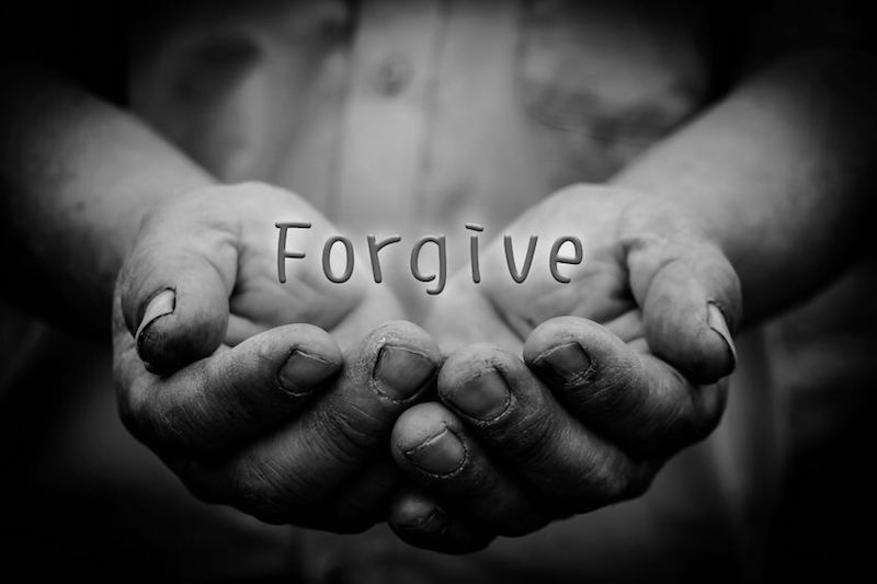 The power to forgiven showing the word forgiveness written with a man's hands under