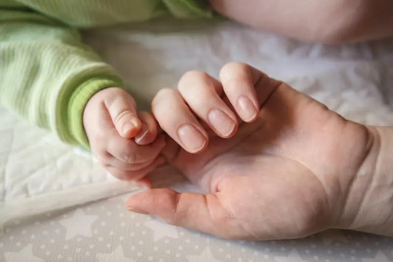 how to touch God showing a mother holding the hand of the baby