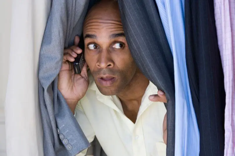 dangers of unconfessed sin showing a man hiding to make a phone call